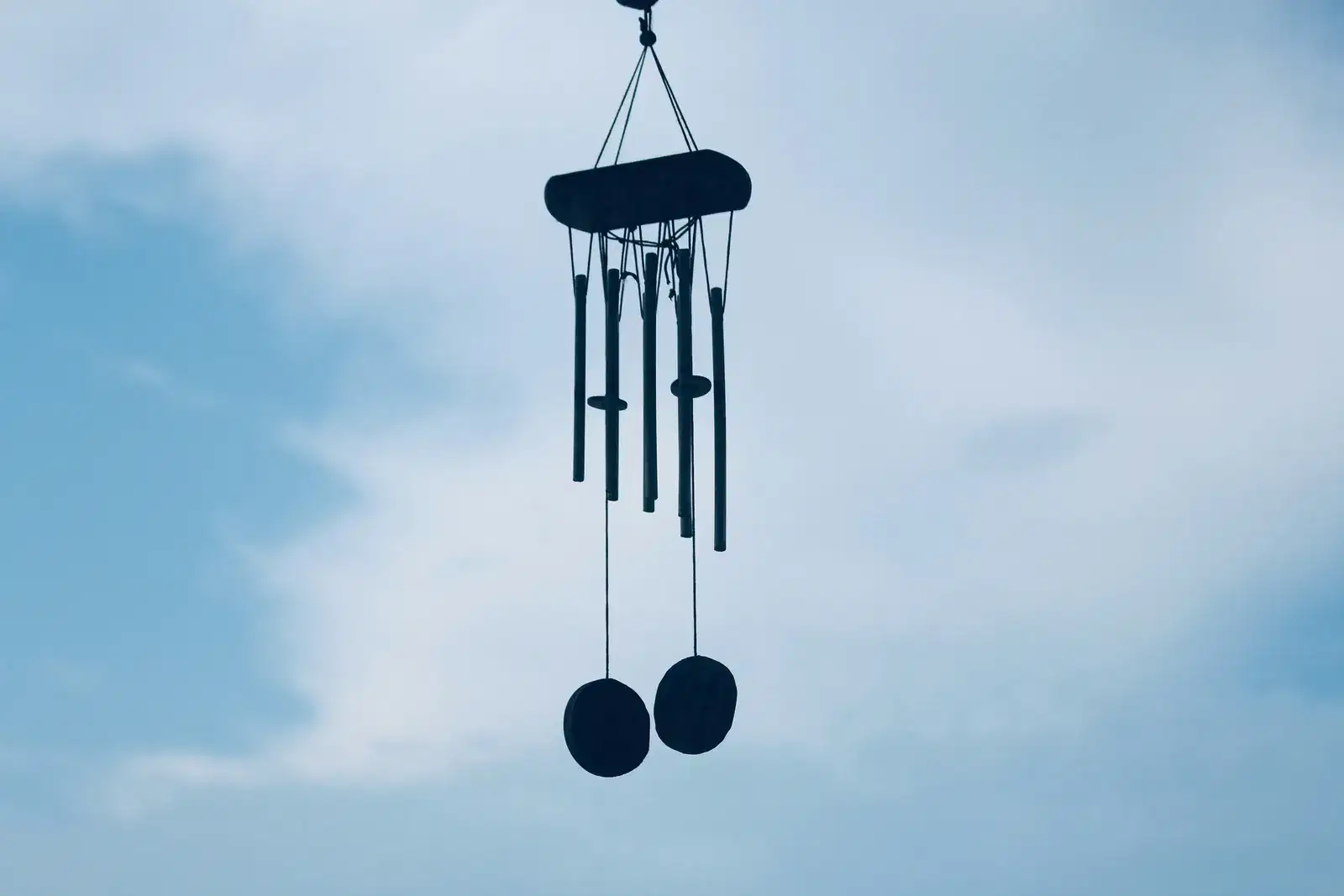 A wind chime hanging against a soft blue sky, a reminder that communication and emotional needs deserve to be heard by your partner