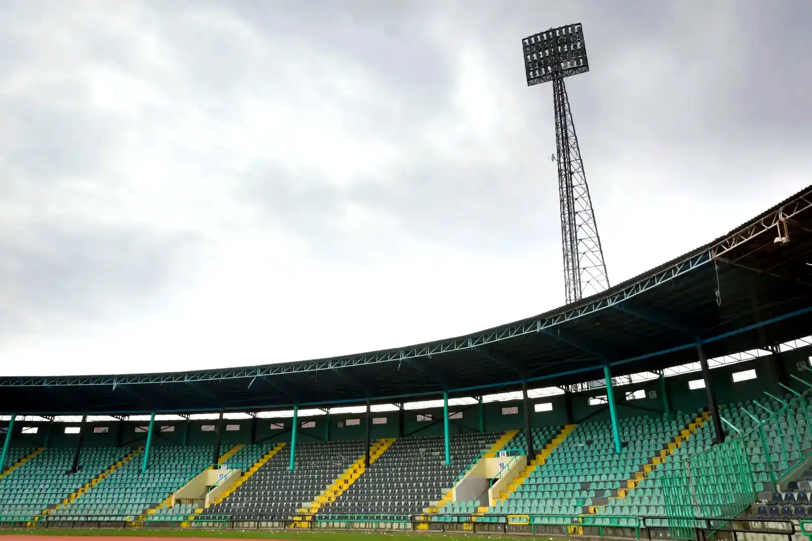 Empty stadium stands and a floodlight under a cloudy sky, evoking how sports betting can quietly turn into a betting addiction.