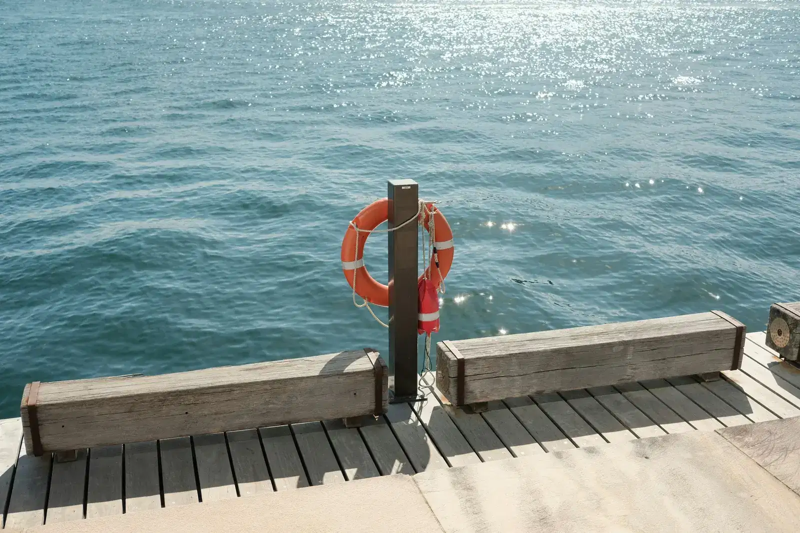 A life ring hanging on a wooden pier over open blue water, safety within reach, a reminder that a panic attack is a false alarm that raises your heart rate, and the fear of dying it brings will pass.