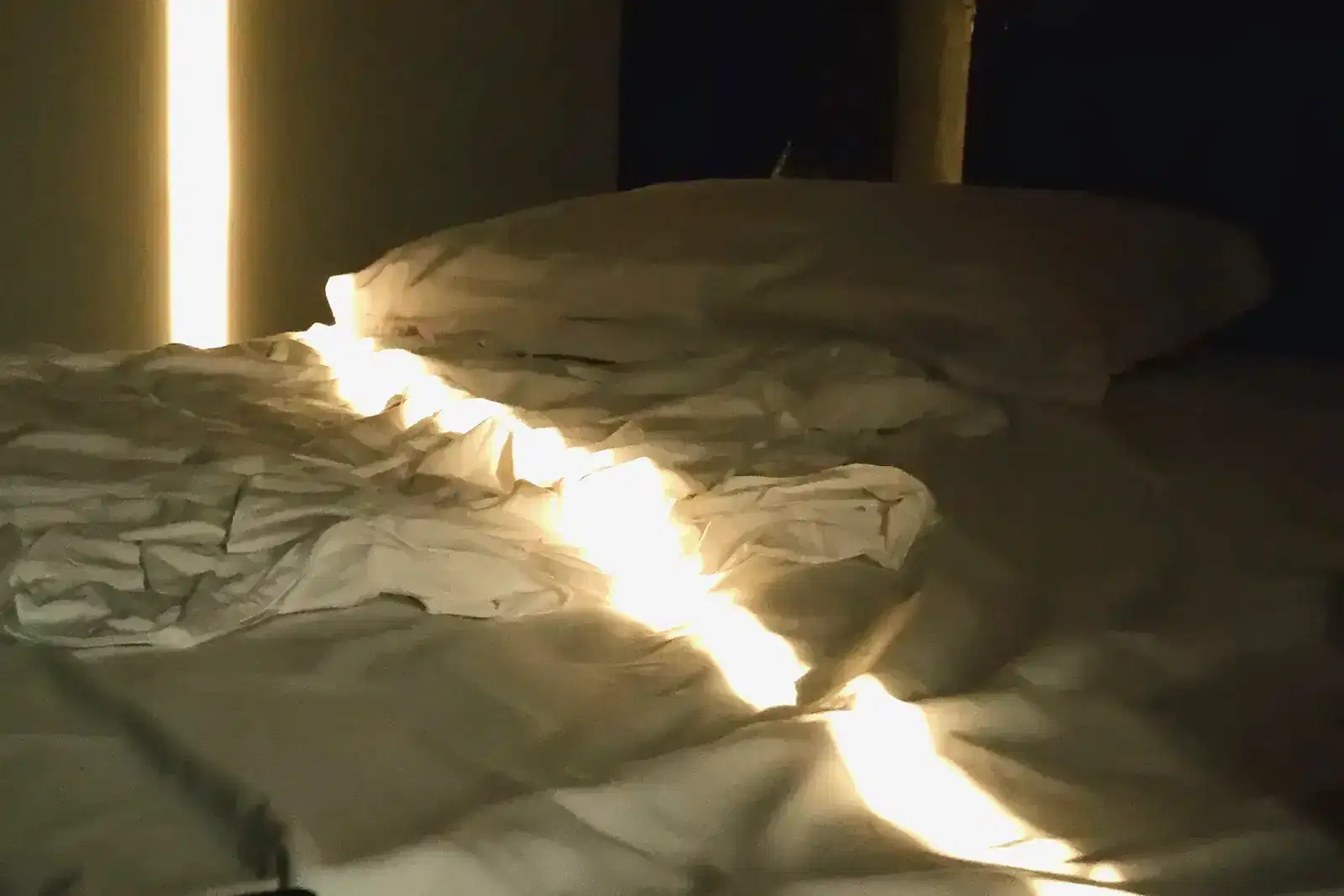 Morning light falling across rumpled sheets on an empty bed, the quiet after nocturnal panic attacks and waking up in a panic, when sleep anxiety and trouble sleeping can follow.