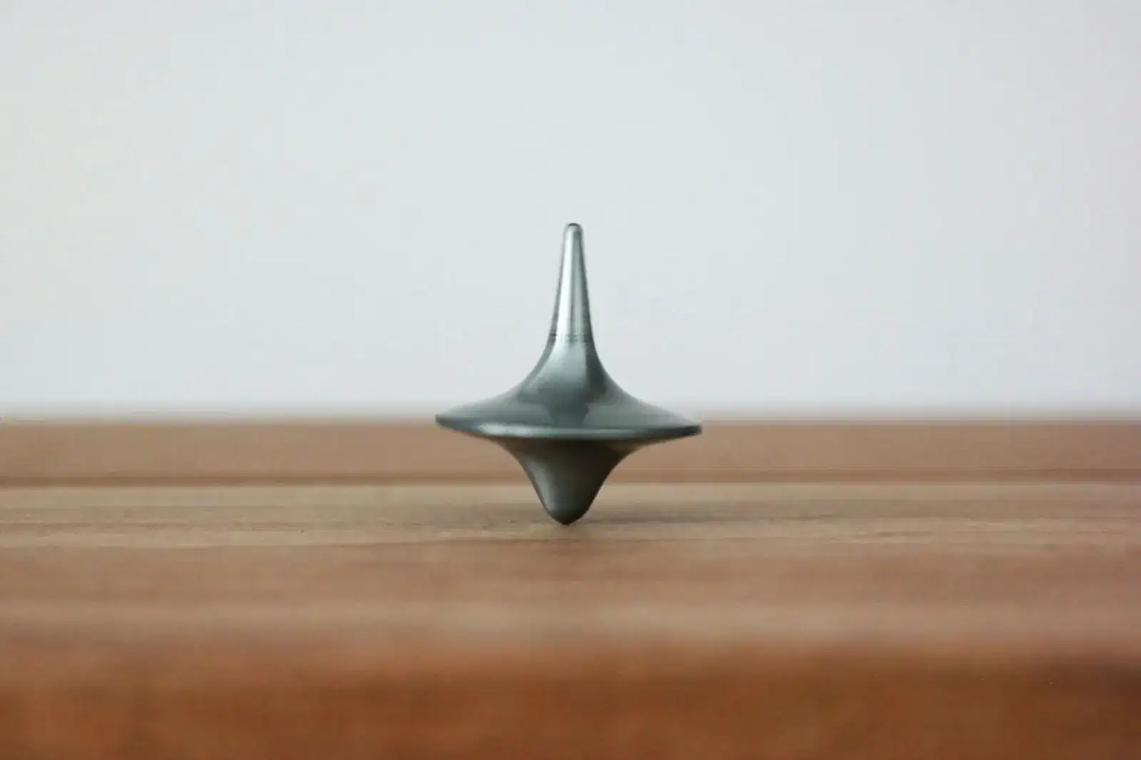 Silver spinning top balancing on a wooden table, like a parent keeping their balance through parenting stress and family life