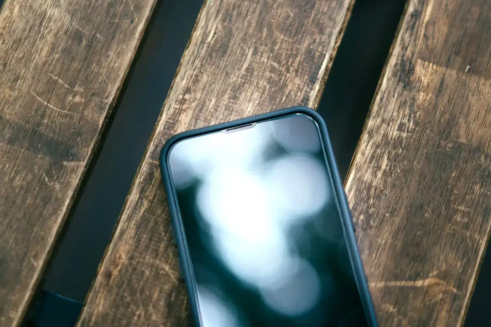 Phone with its screen switched off on a wooden bench, a reminder that stepping away from online gambling apps and online casino sites helps you quit gambling.