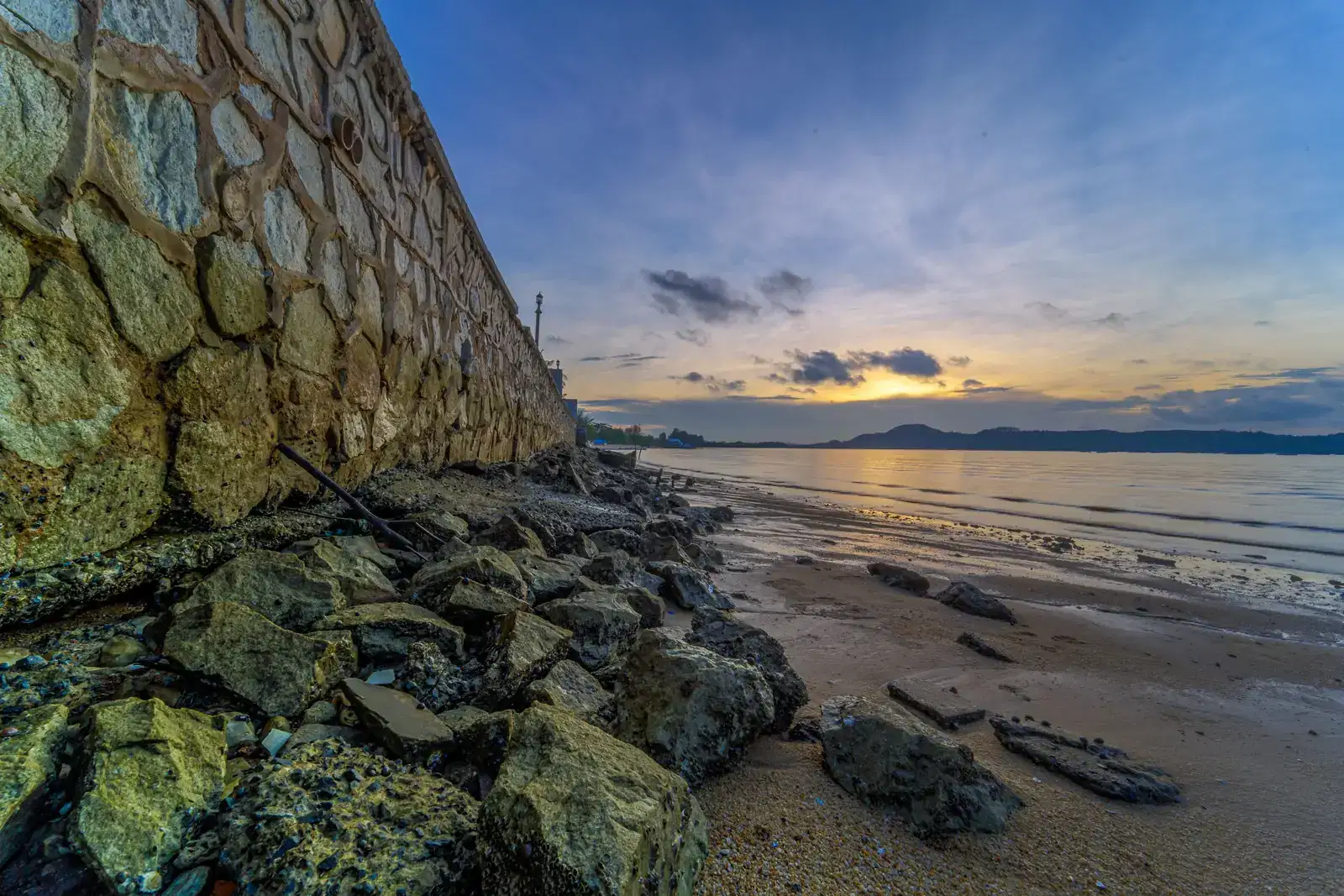 Old stone seawall and rocks at sunset, a quiet image of how a gambling problem builds slowly before the warning signs become clear.