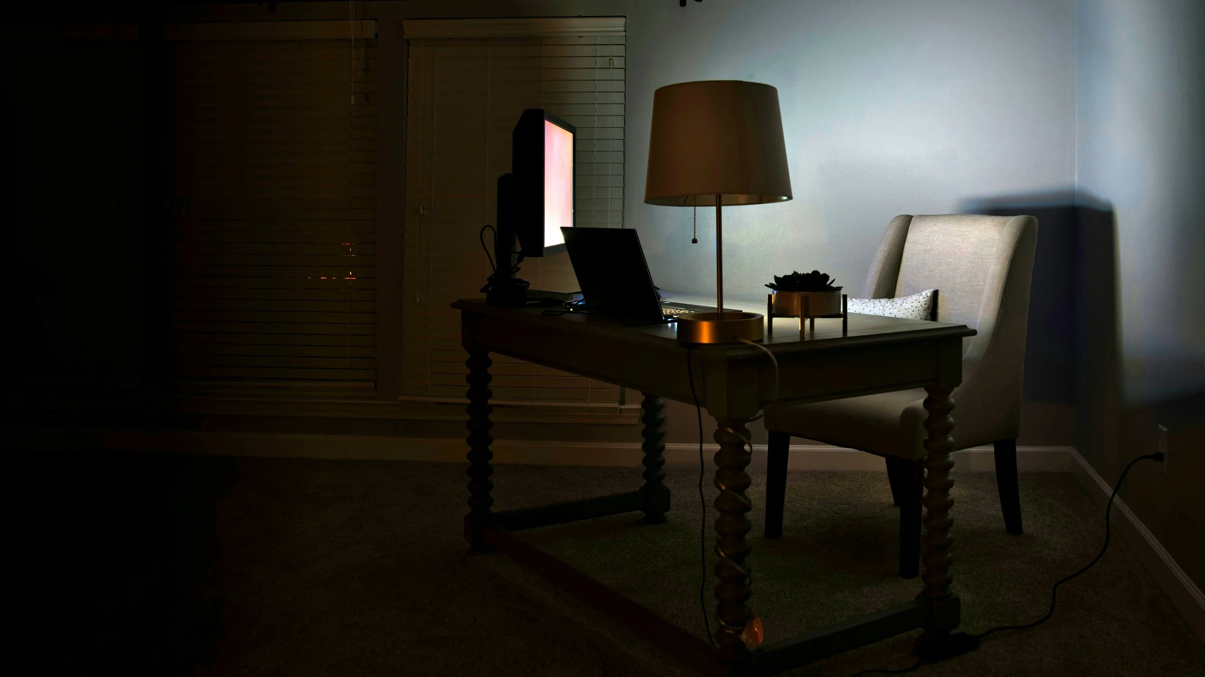 A quiet desk and lamp in a dark room at home, ready for virtual counselling