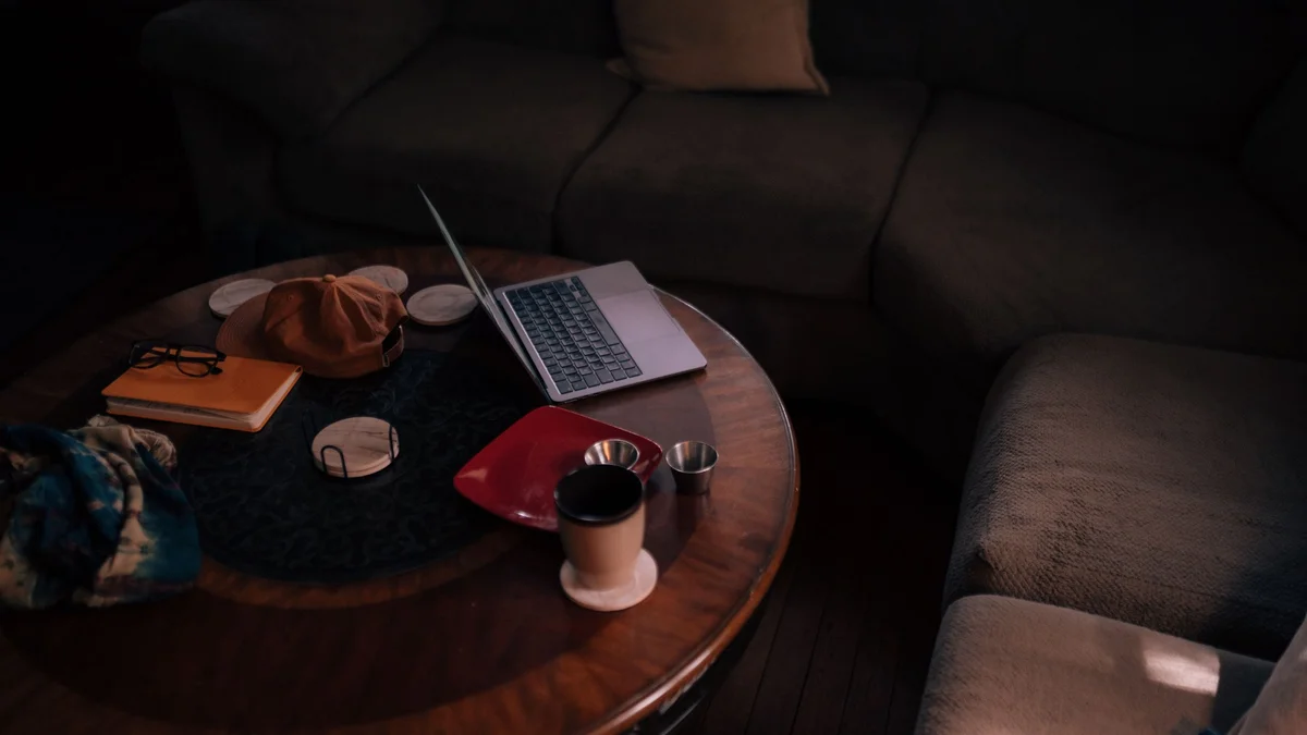 A laptop open on a coffee table in a dim living room, an evening of online therapy from home