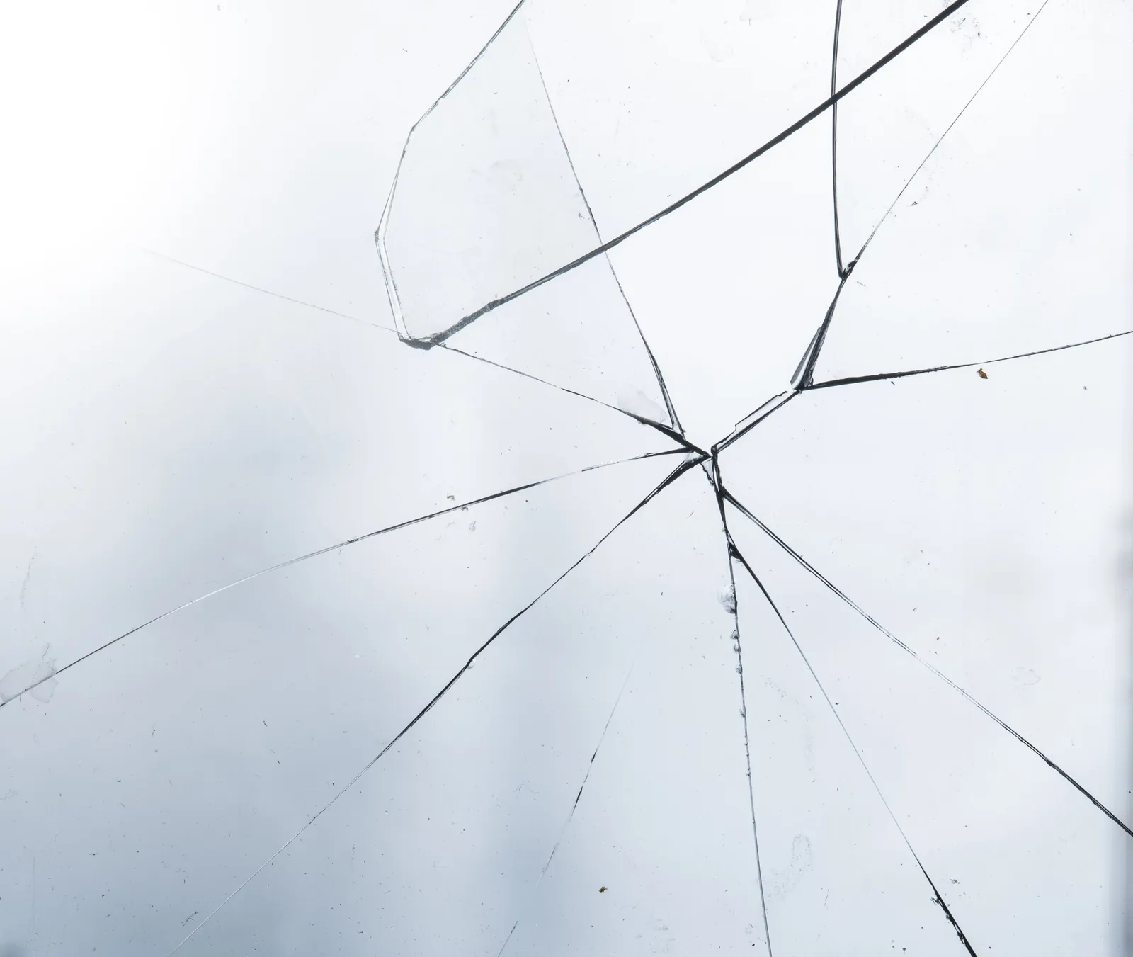 Fine cracks spreading across a pane of pale glass in soft light, an image for affair recovery therapy