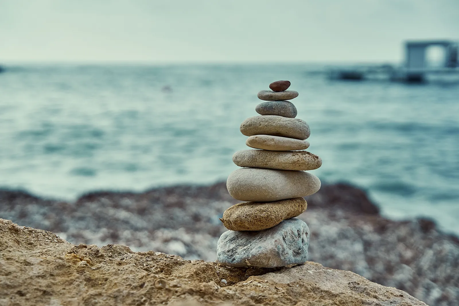 A balanced stack of smooth stones on a rocky shore by the sea, an image for Gottman therapy