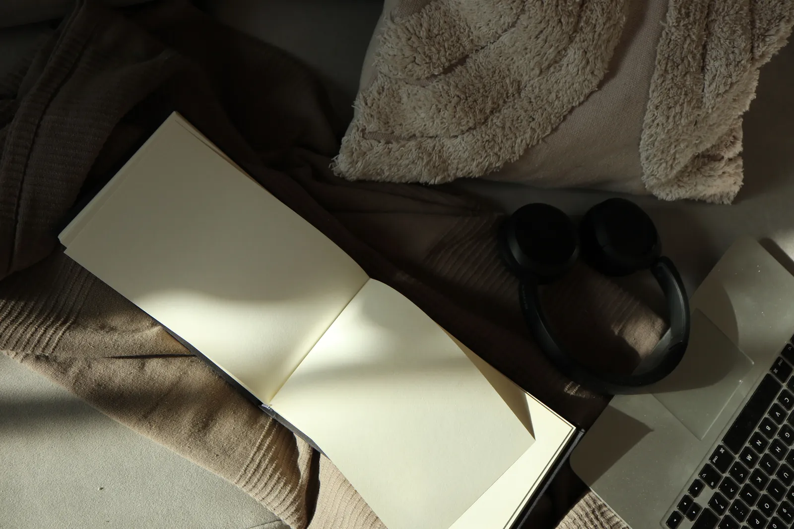 Headphones resting on a soft blanket beside an open notebook and laptop, an image for online couples counselling from home